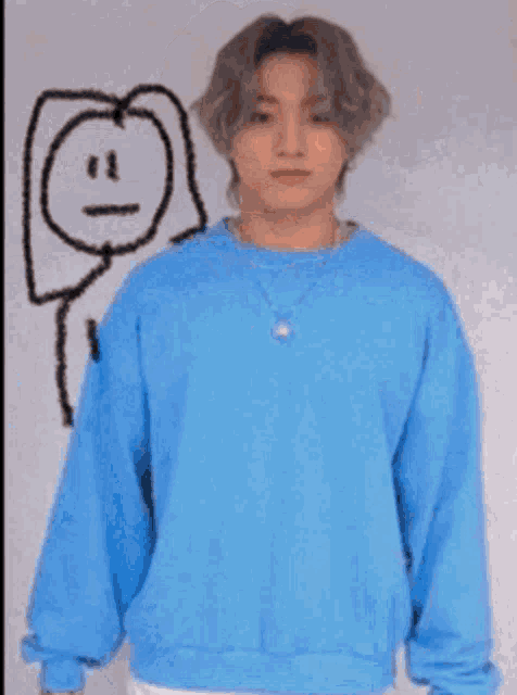 a young man wearing a blue shirt and a necklace with a drawing of a face on it .