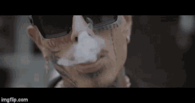 a man with tattoos on his face is smoking an electronic cigarette .