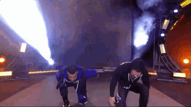 two men are standing on a stage with smoke coming out of them