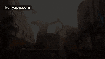 a statue of a man holding a sword is in the middle of a city street with buildings in the background .