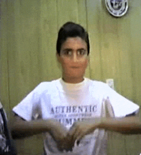 a boy wearing a white authentic t-shirt is making a funny face