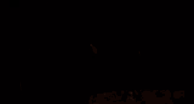 a woman is standing in front of a glowing object in a dark room