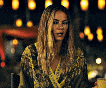 a woman with long blonde hair is wearing a green and yellow floral kimono