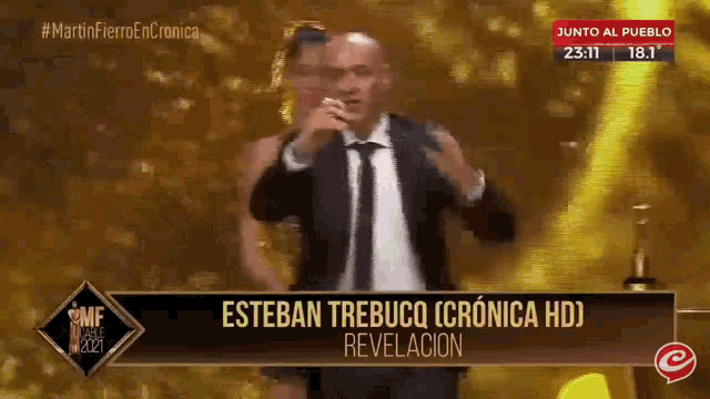 a man in a suit and tie stands in front of a sign that says esteban trebuco cronica hd revelacion
