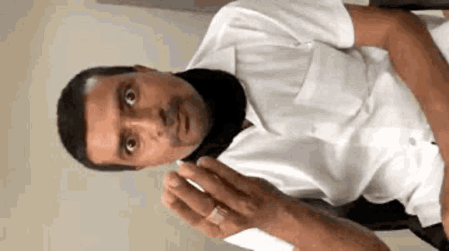 a man in a white shirt is sitting in a chair holding a cell phone