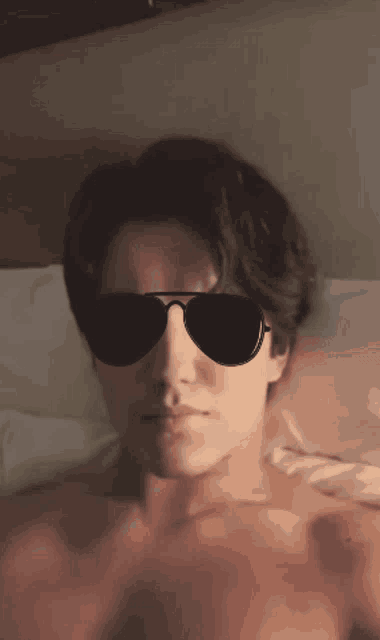 a man without a shirt is wearing sunglasses