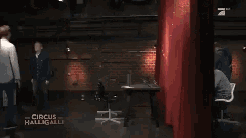 two men are standing in a room with the words circus halligalli on the bottom