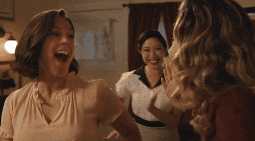 a woman is laughing while another woman holds her hand to her mouth
