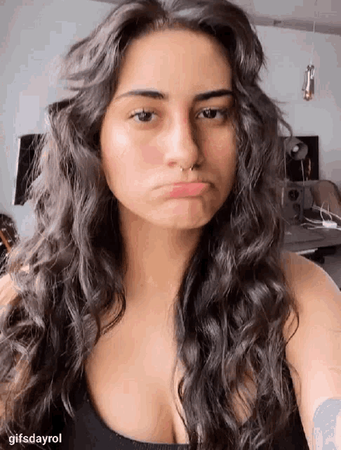 a woman with long hair and a nose ring is making a funny face .