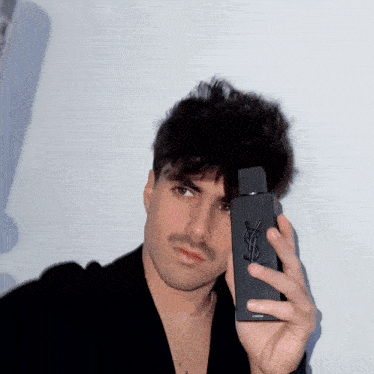 a man holding a bottle of yves saint laurent cologne