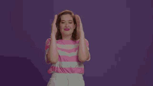 a woman in a pink and white striped shirt is clapping