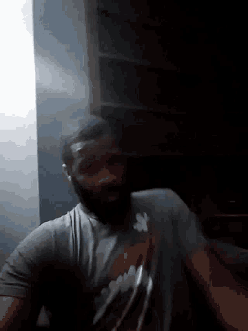 a man in a grey shirt is laying on his back with his head on the floor
