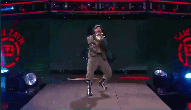 a man in a suit and boots is standing on a stage holding a microphone .