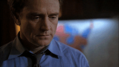 a man wearing a blue shirt and tie is looking down