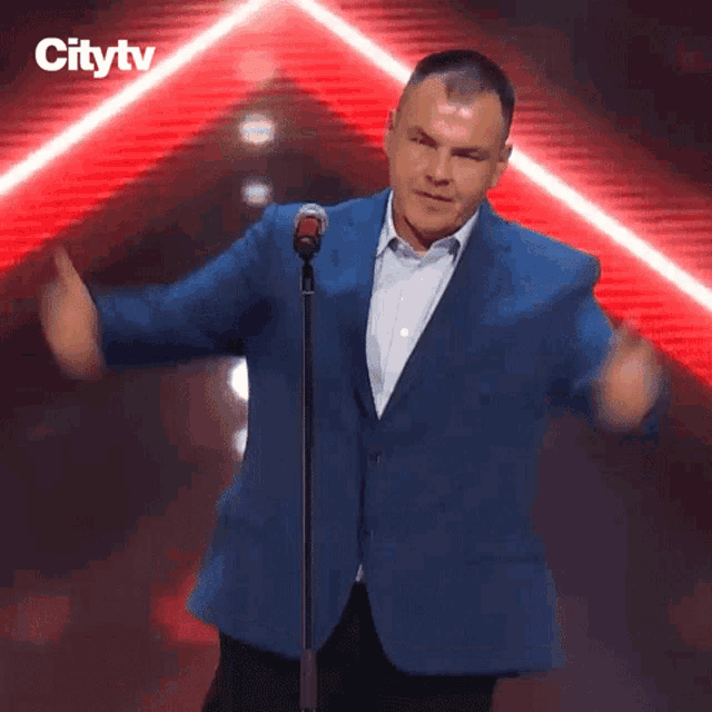 a man in a blue jacket stands in front of a microphone with the word citytv on the bottom right