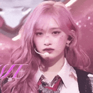 a woman with pink hair is wearing a tie and a microphone