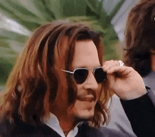 a man with long hair is wearing sunglasses and adjusting them