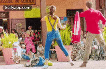 a man and a woman are dancing on the street in front of a crowd of people .