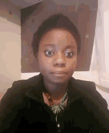 a woman with a nose ring is making a funny face while wearing a black jacket