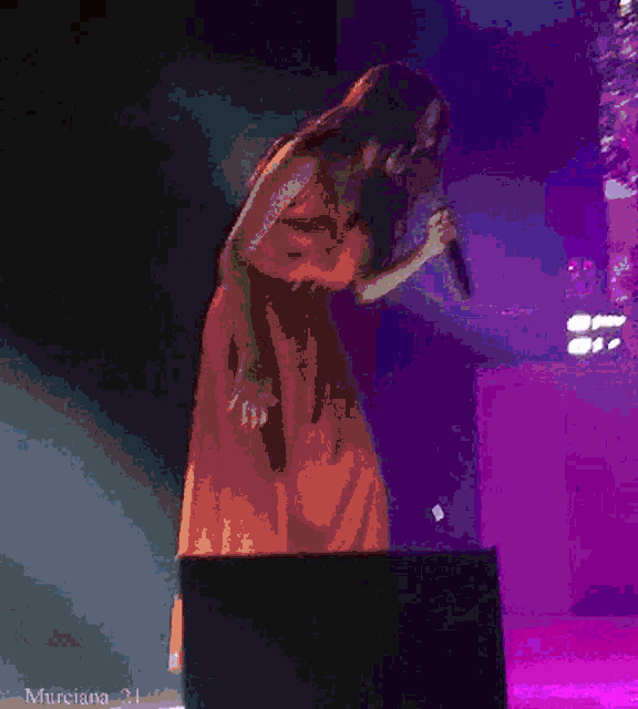 a pixelated image of a woman singing into a microphone with murciana 21 written below it