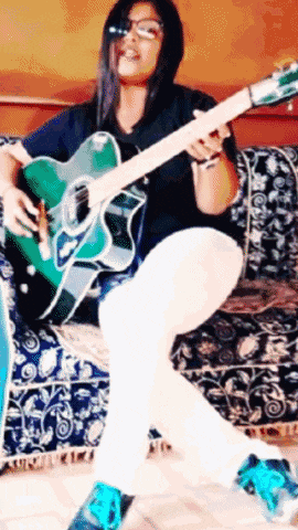 a woman is sitting on a couch holding a guitar