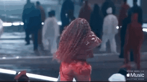 a woman with red hair is dancing on a stage in front of a crowd of people .