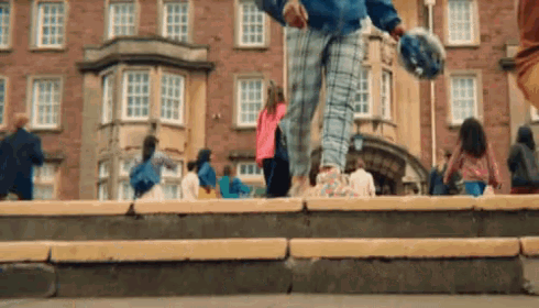 a group of people are walking down stairs in front of a large brick building