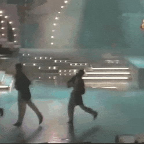 a group of people are walking on a stage in front of a crowd