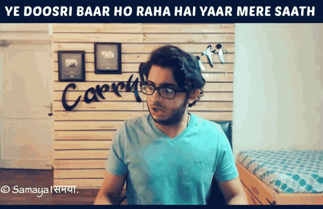 a man wearing glasses and a blue shirt stands in front of a wall that says carrot
