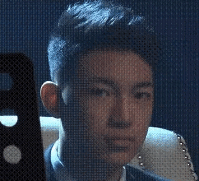 a young man in a suit is sitting in a chair and looking at the camera