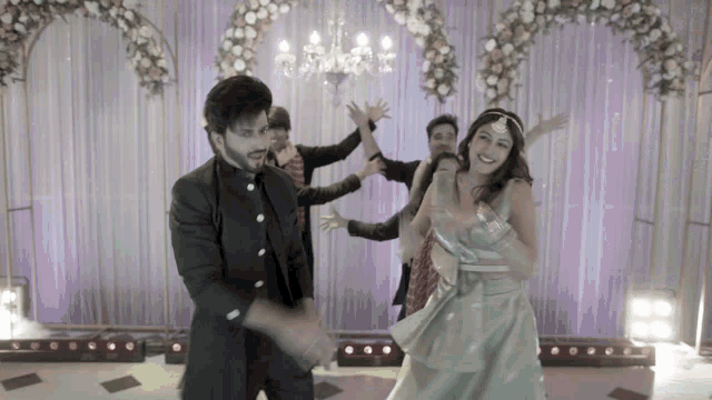 a man and a woman are dancing in front of a purple curtain