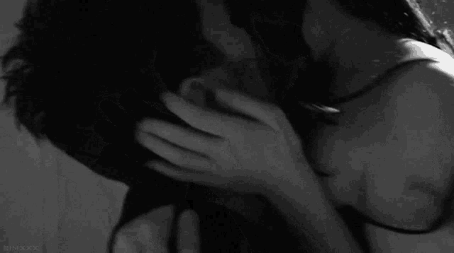 a black and white photo of a woman kissing a man 's neck
