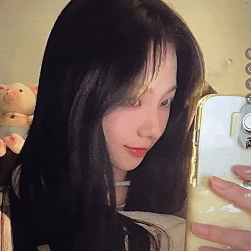 a woman with long black hair is taking a selfie with her phone .