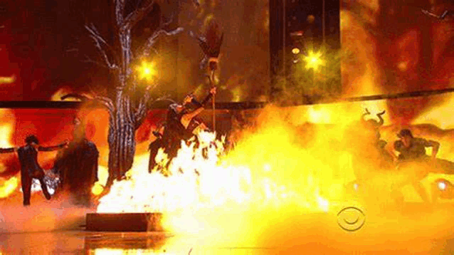 a group of people are dancing in front of a fire .