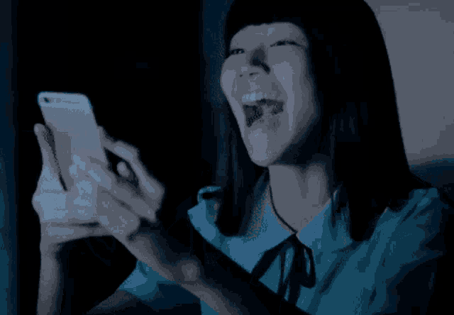 a girl is laughing while looking at a cell phone