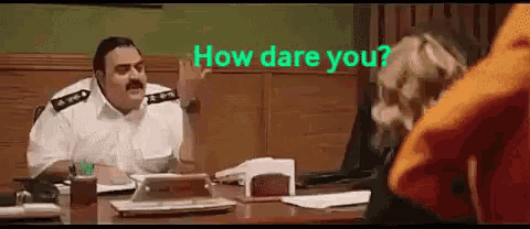 a man with a mustache is sitting at a desk talking to a woman and the words how dare you are above him .