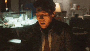 a man wearing a turtleneck and a jacket is smiling in a dark room