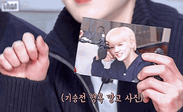 a person holding a picture of a man with korean writing