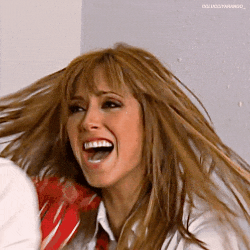 a woman is laughing with her mouth open and her hair is blowing in the wind