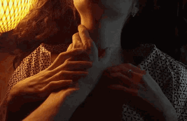 a close up of a woman 's neck with a man 's hands on it .