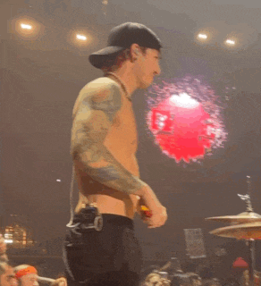 a man without a shirt is standing on a stage holding a microphone .
