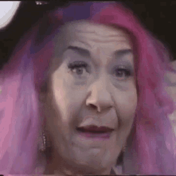 a close up of a woman with pink and purple hair making a face .
