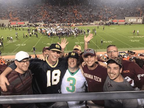 a group of men are posing for a picture in front of a football field