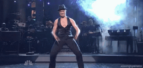 a man in a fedora is dancing on a stage in front of a band .