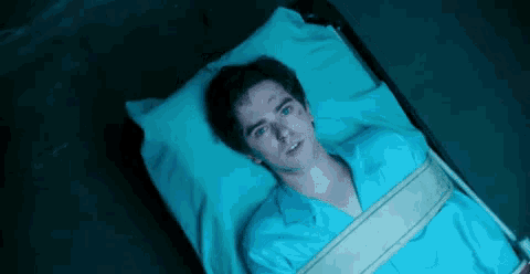 a man is laying in a hospital bed with a bandage around his neck .