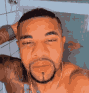 a shirtless man with a beard taking a selfie