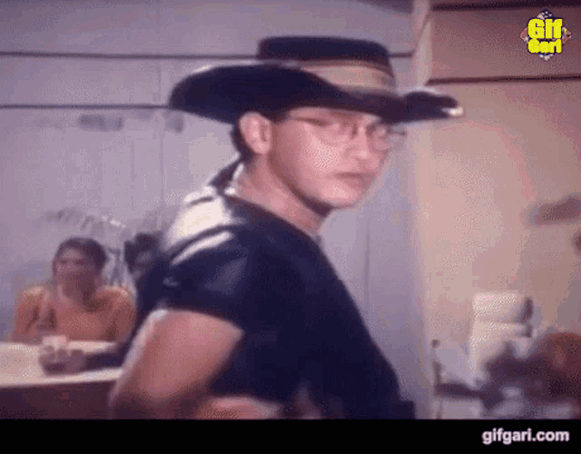 a man in a cowboy hat and glasses is standing in a room .