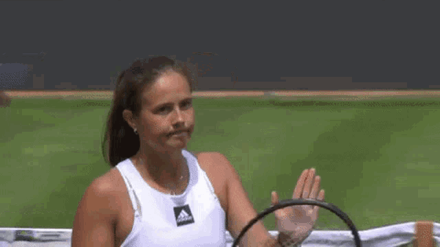 a woman is holding a tennis racquet on a tennis court while another woman looks on .