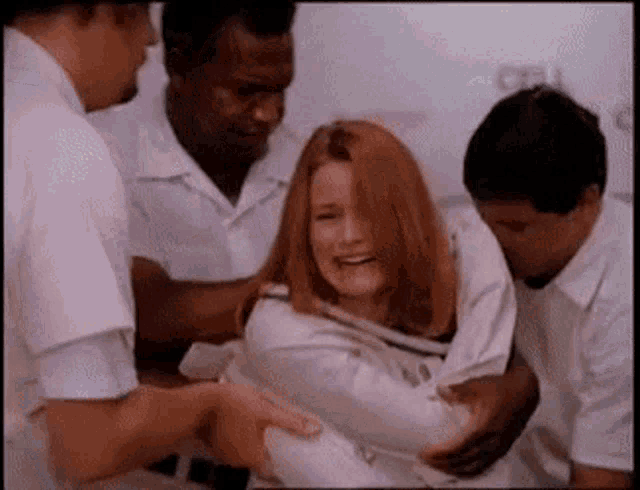 a woman in a straight jacket is being held by a group of people