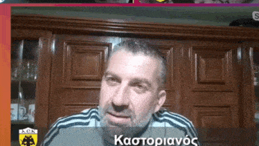 a man with a beard is wearing a gray and black adidas shirt